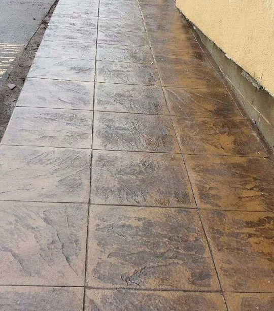 A sidewalk with tiles on it next to a building.