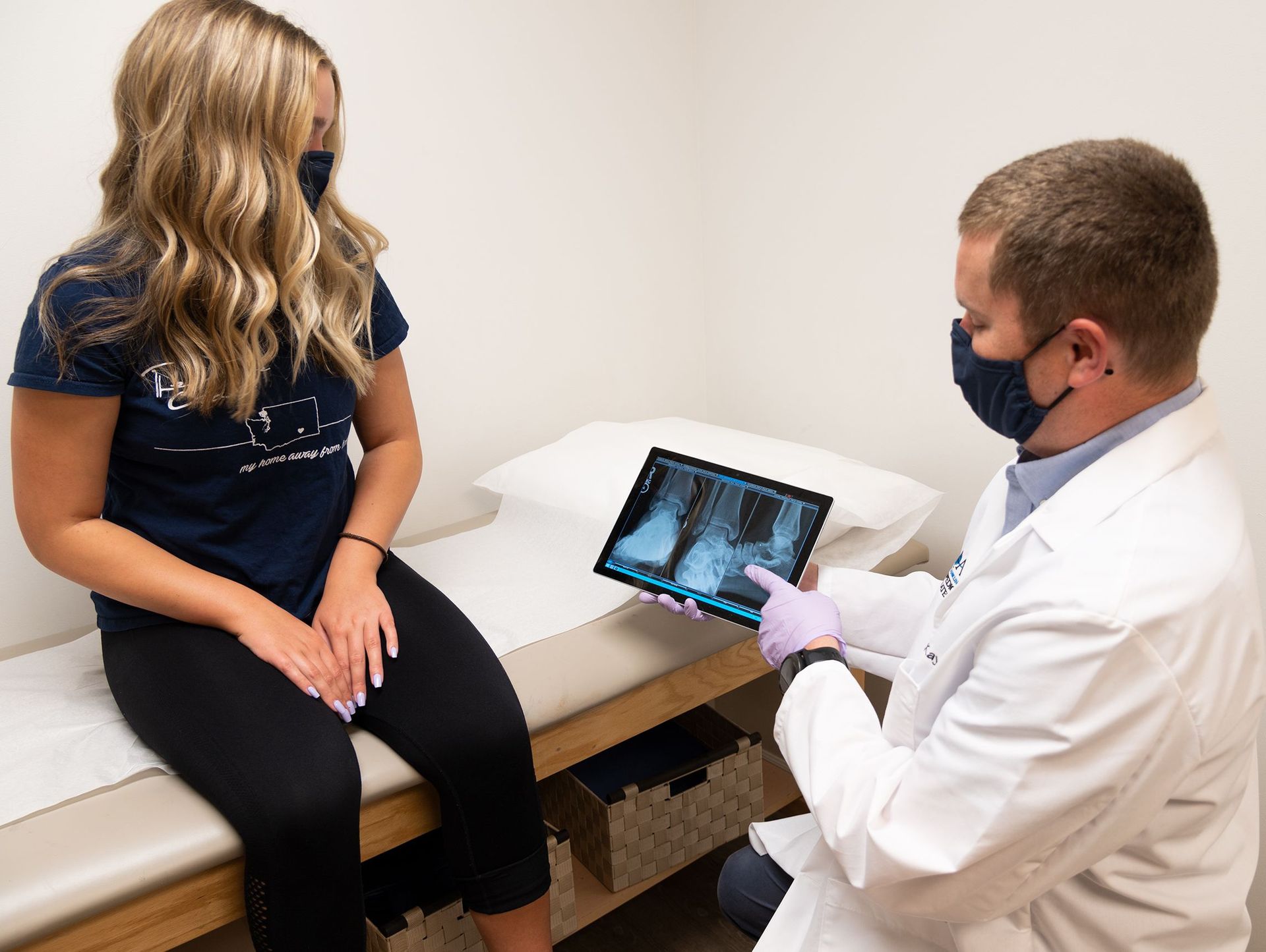 Doctor is showing an x-ray of a knees to a patient with blonde hair.