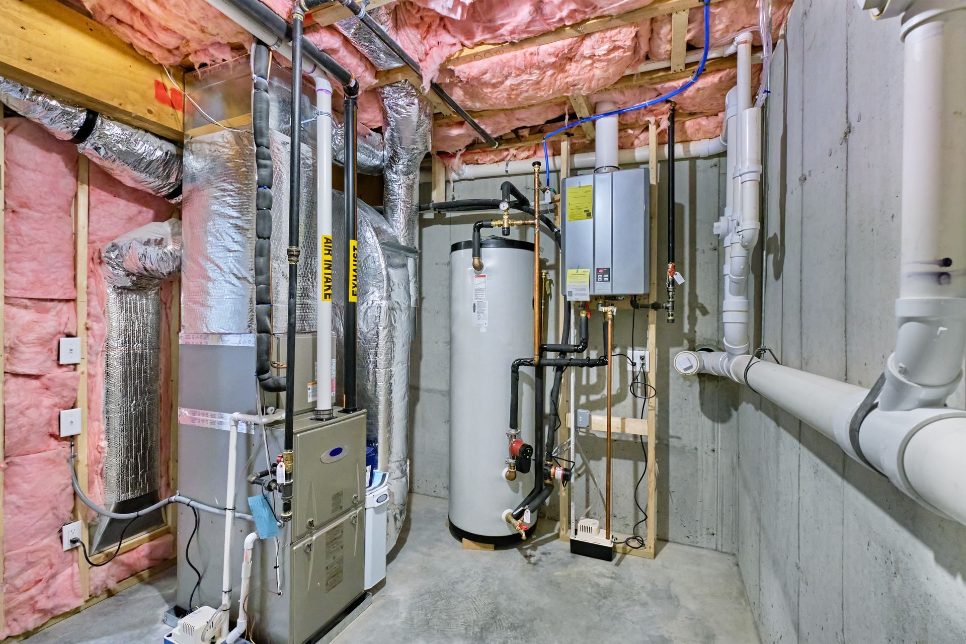 Basement utility room with water heater, furnace, exposed pipes, and insulation.