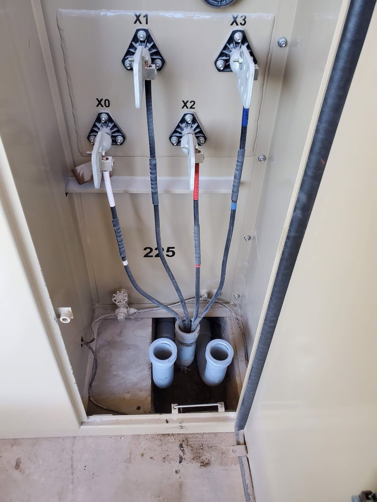 Interior of a transformer cabinet showing four labeled terminals (X0, X1, X2, X3) with connected electrical cables.