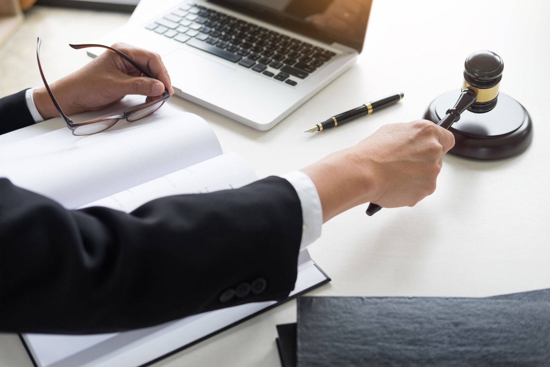 Lawyer signing documents at a desk beside a laptop and gavel