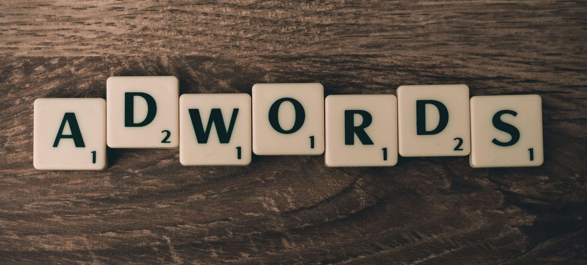 Scrabble tiles spell out the word adwords on a wooden table