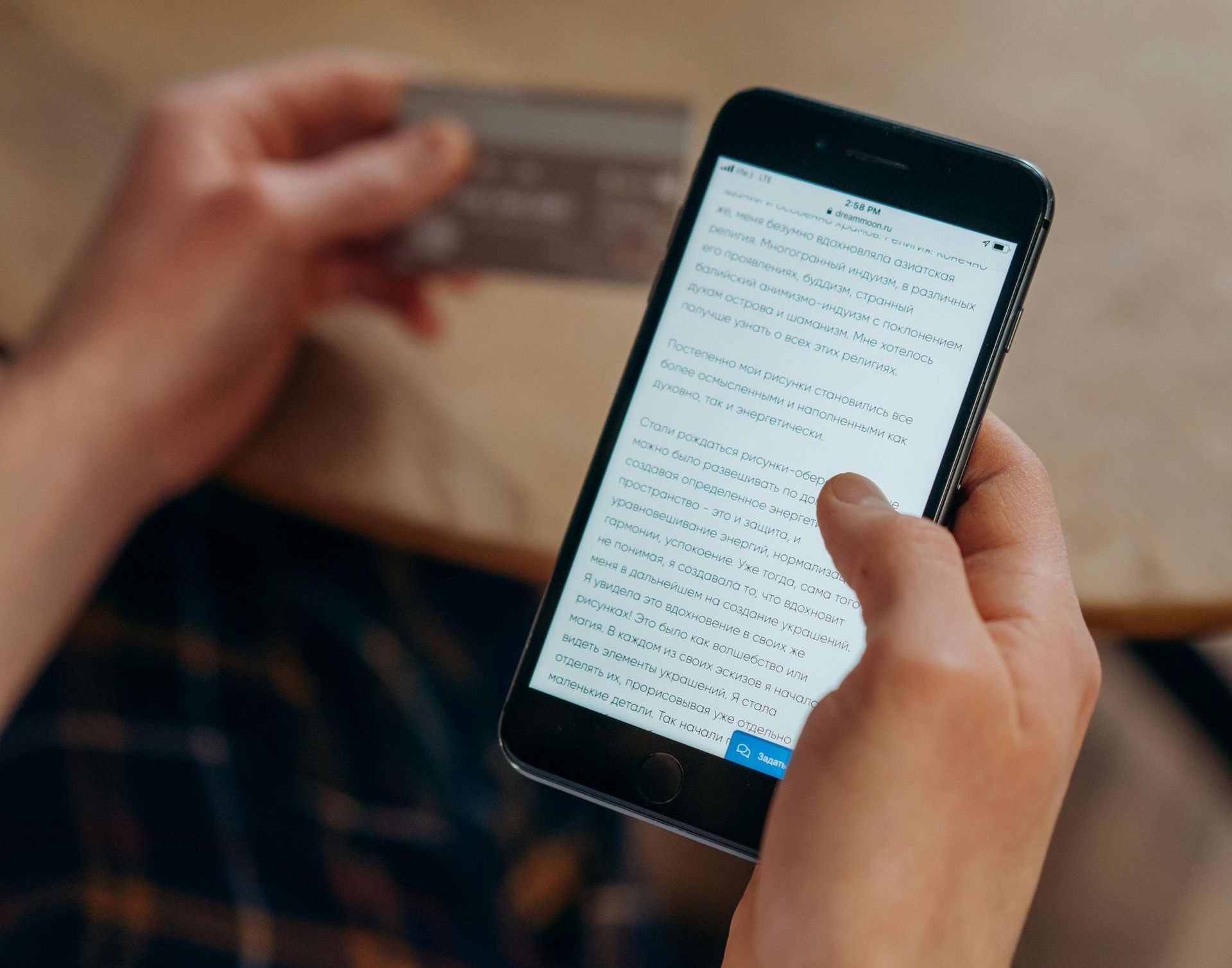 A person is holding a credit card and a cell phone.