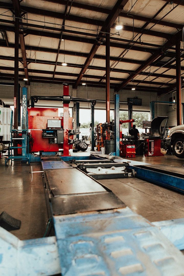 Auto repair shop interior with blue and red lifts, tools, and a vehicle.