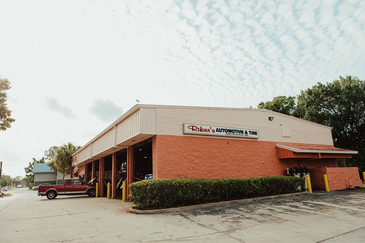 Exterior view of a commercial building with a red brick facade, a sign, and a red truck parked outside.