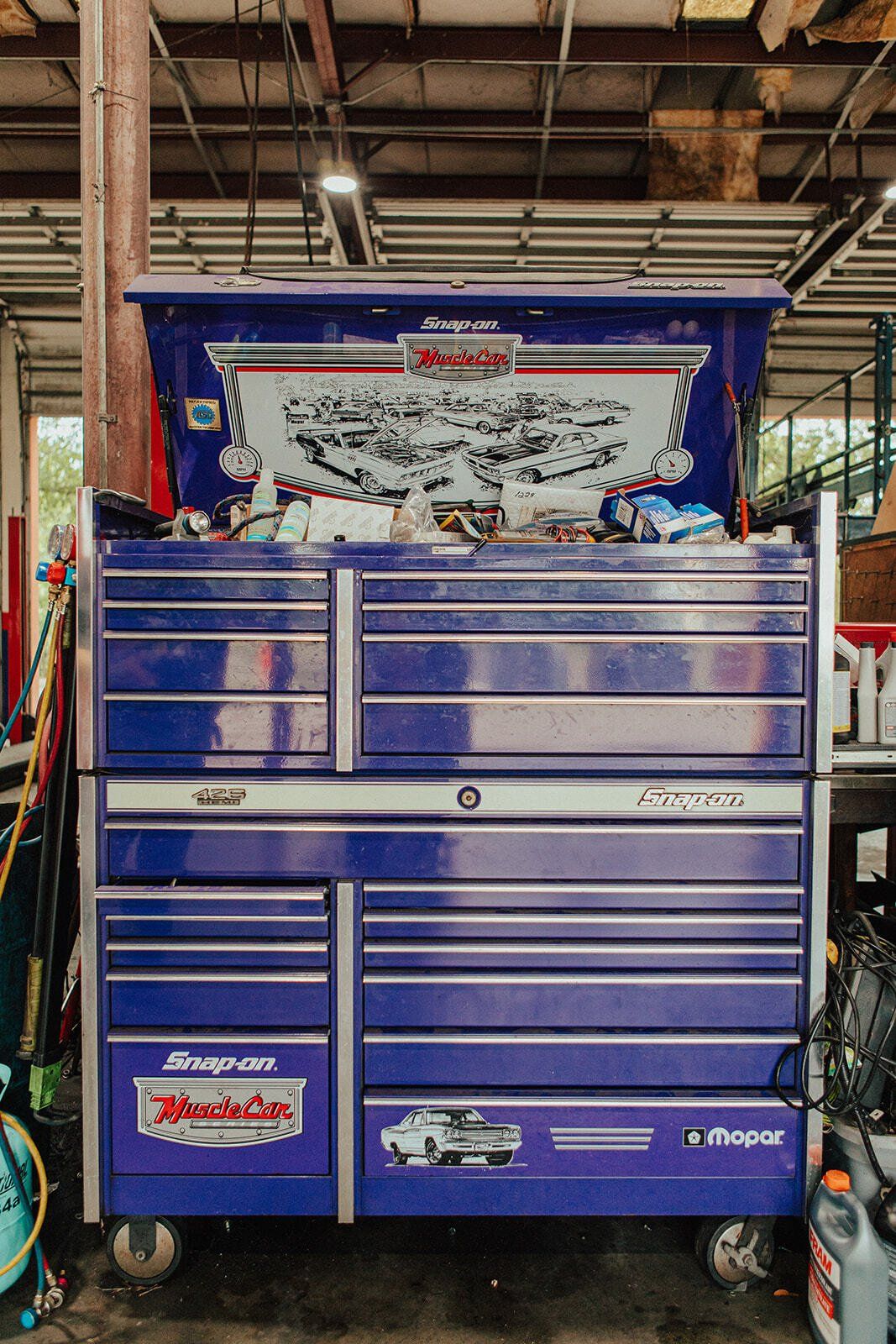 Blue Snap-on tool chest with drawers open, in a workshop. It is on wheels, with a custom graphic on top.