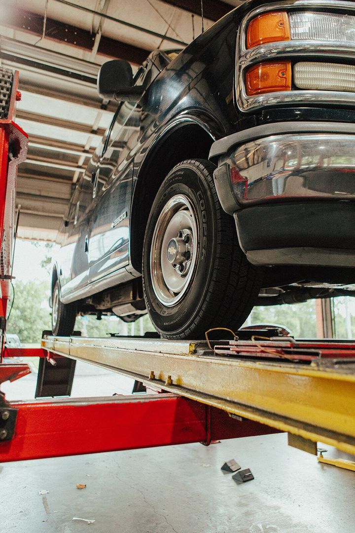 Black van on a red and yellow car lift inside a garage.