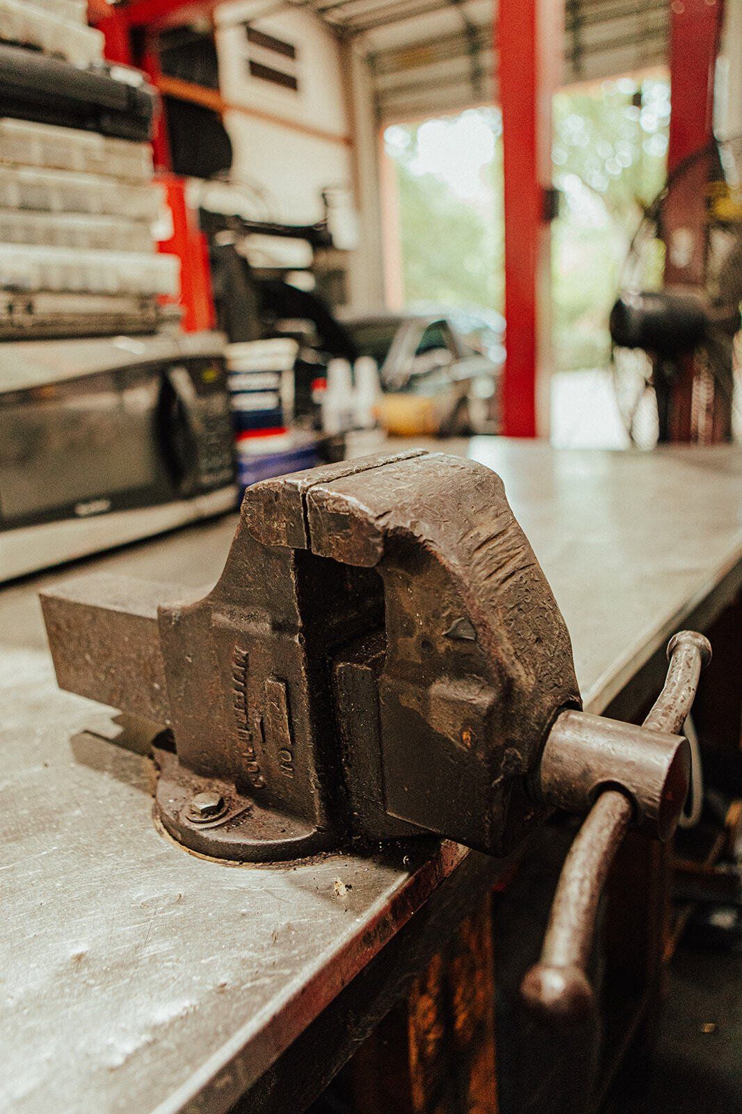 A rusty metal vise on a workbench in a garage.
