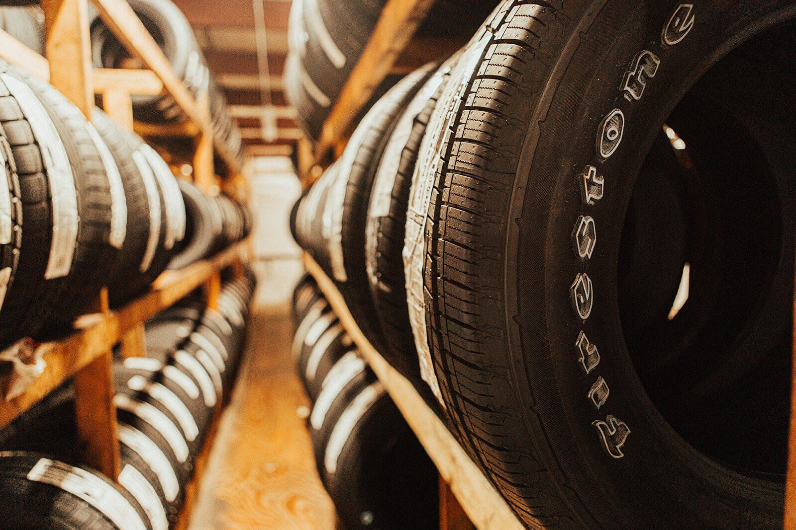 Tires stacked on wooden shelves in a storage room. Firestone brand visible.
