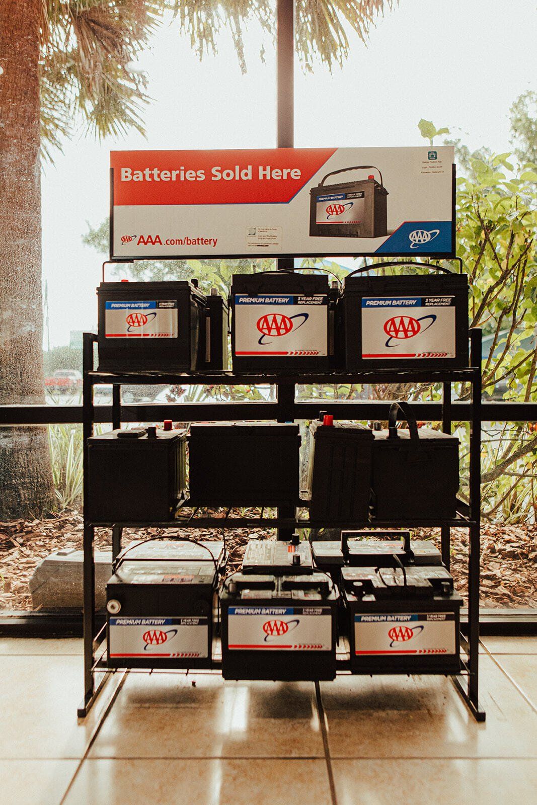 Display of car batteries for sale in a store. Sign reads 