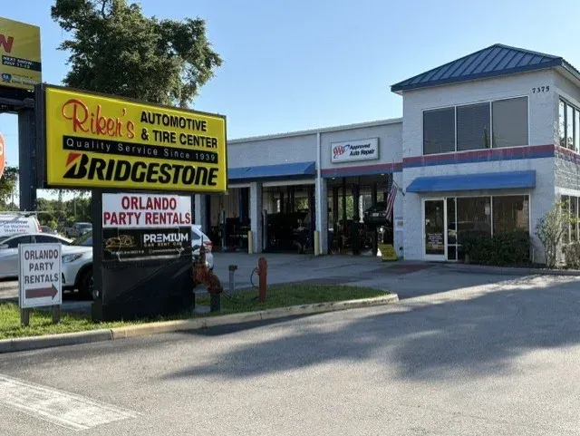 Exterior of a Pep Boys auto repair shop with multiple bays, cars on lifts, and a sign.