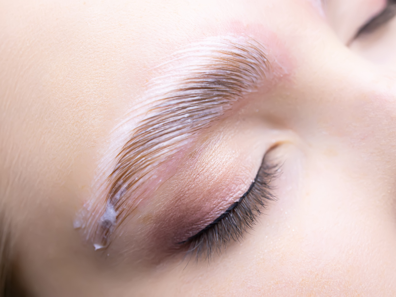 Close-up of a person's eye and eyebrow undergoing a brow lamination treatment.