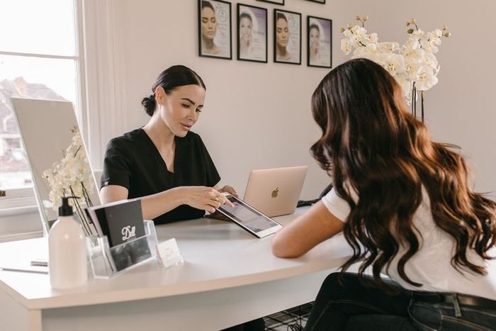 A woman consults with a healthcare provider at a desk in a well-lit office.