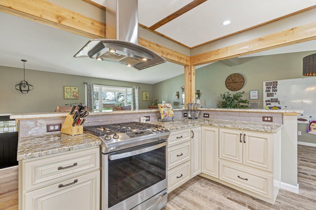 Elegant kitchen with marble island, white cabinets, and stainless steel stove under a decorative chandelier
