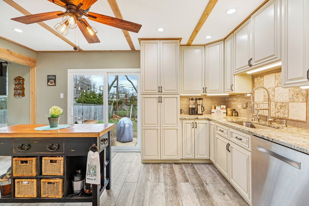 Bright kitchen with white cabinets, wood island, and sliding glass doors opening to a patio.