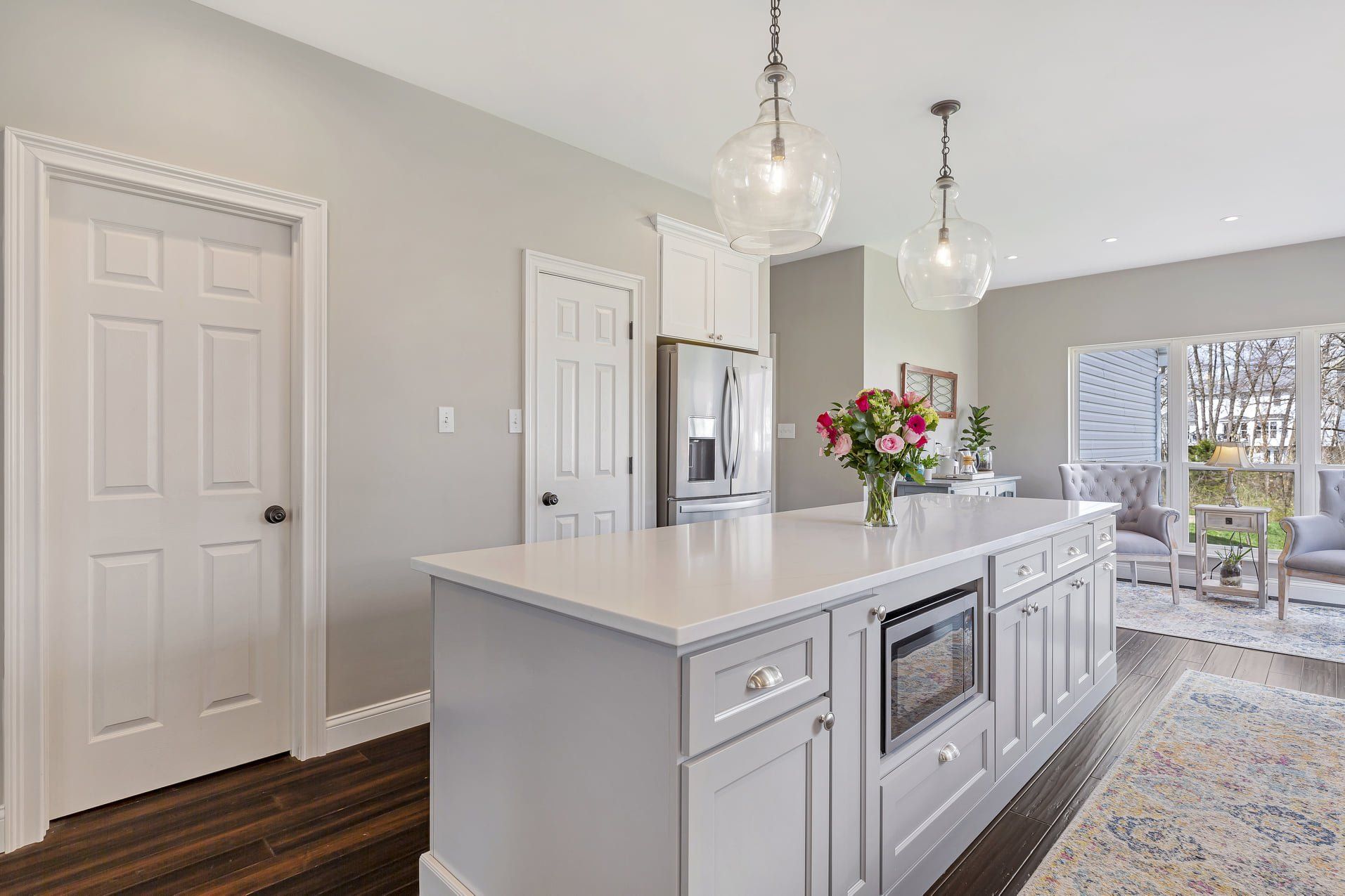 Bright modern kitchen with white island, pendant lights, stainless appliances, and flowers on the counter
