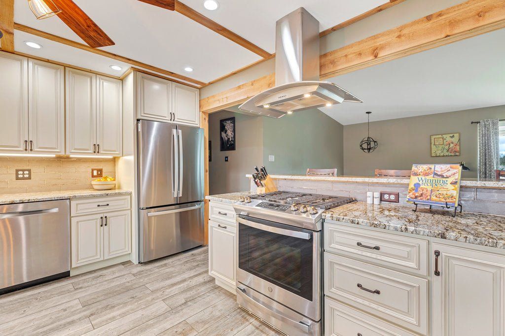 Modern white kitchen with stainless steel appliances, granite island, and pendant lighting