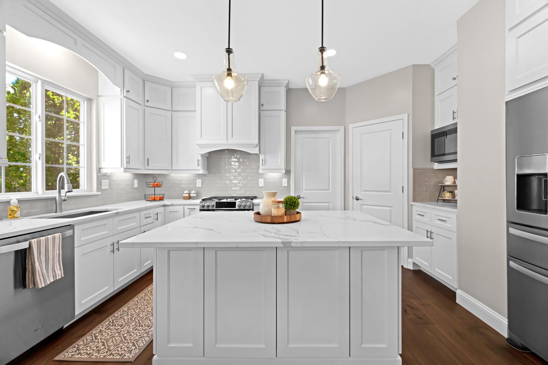 Bright white modern kitchen with central island, stainless appliances, and hardwood floors