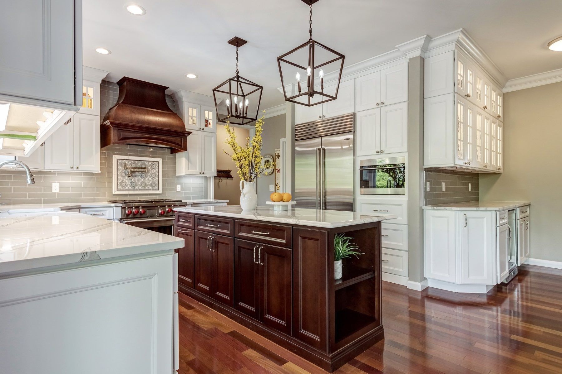 Modern kitchen with dark wood island, white cabinets, stainless refrigerator, and hardwood floors