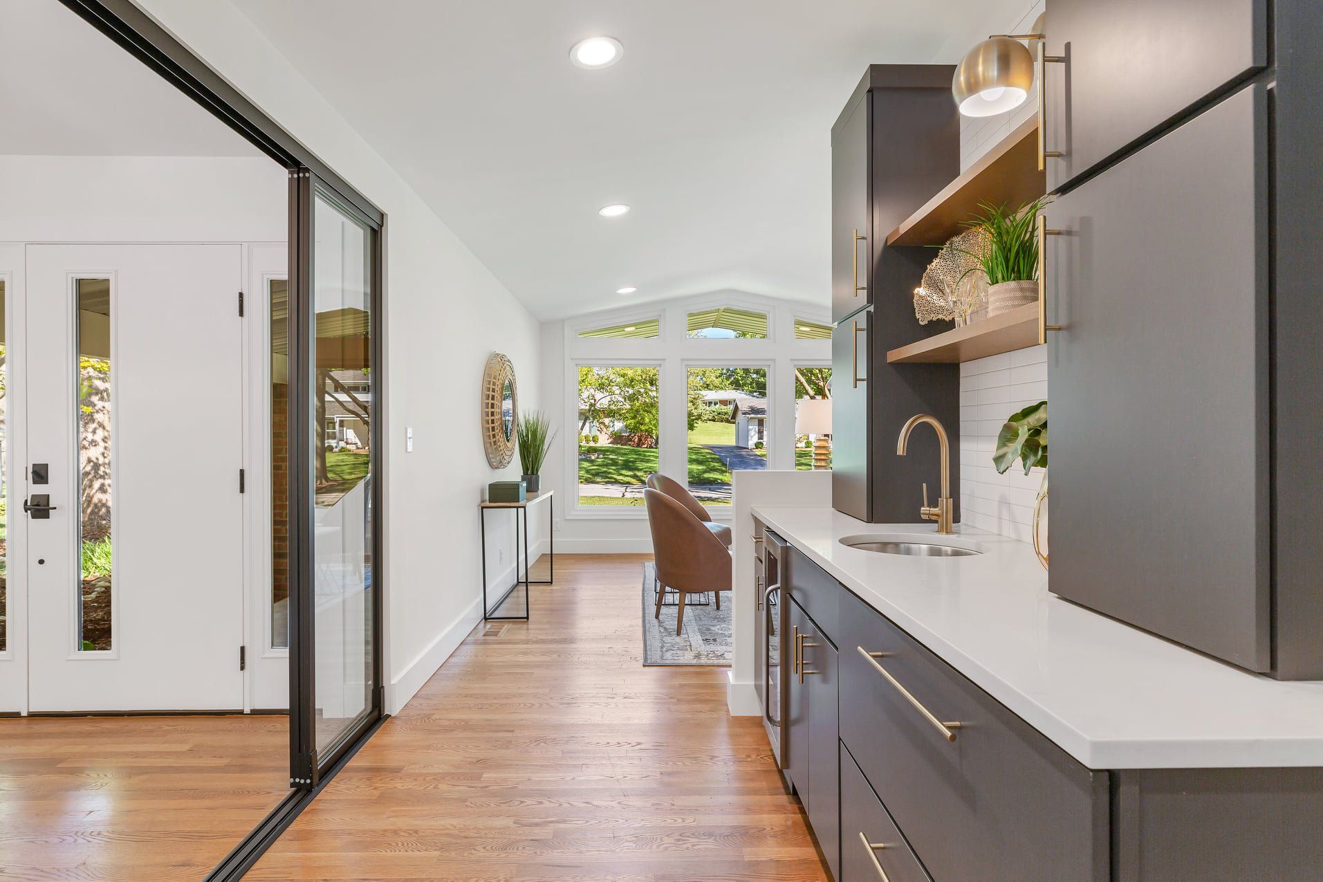 Modern kitchen with gray cabinets, wood floors, and a view of the dining area and backyard doors