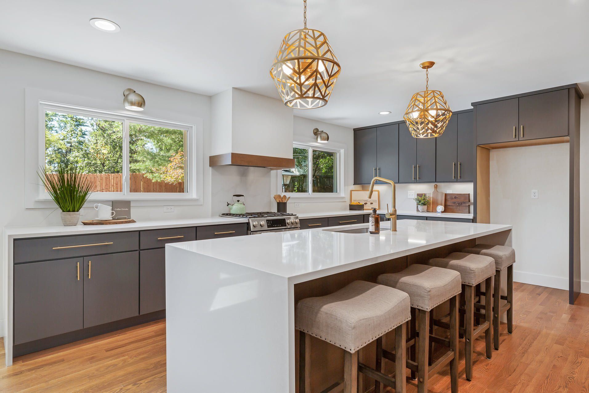 Modern kitchen with white island, gray cabinets, wood floors, and woven pendant lights