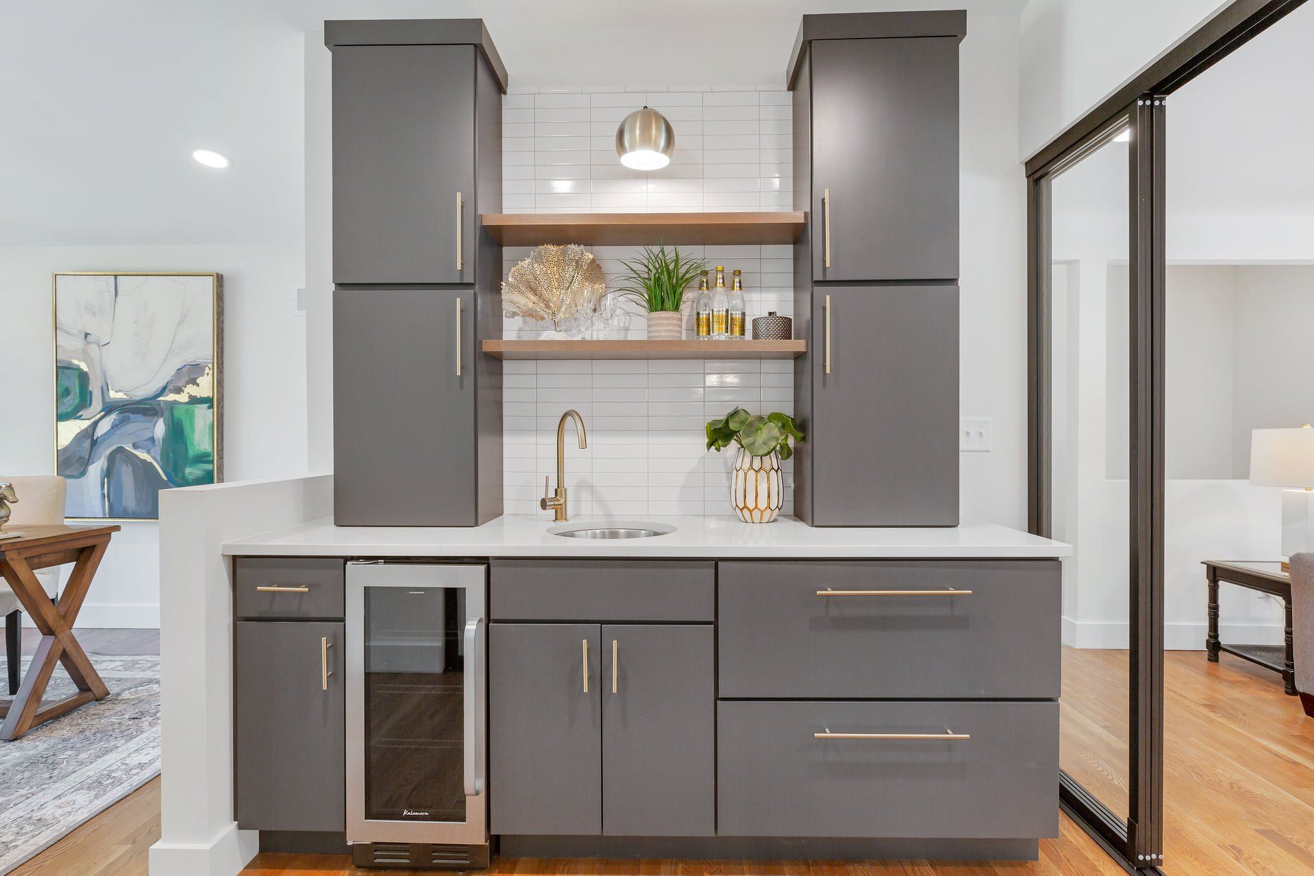 Modern gray kitchen cabinets with white countertops, open shelves, and gold fixtures in a bright room
