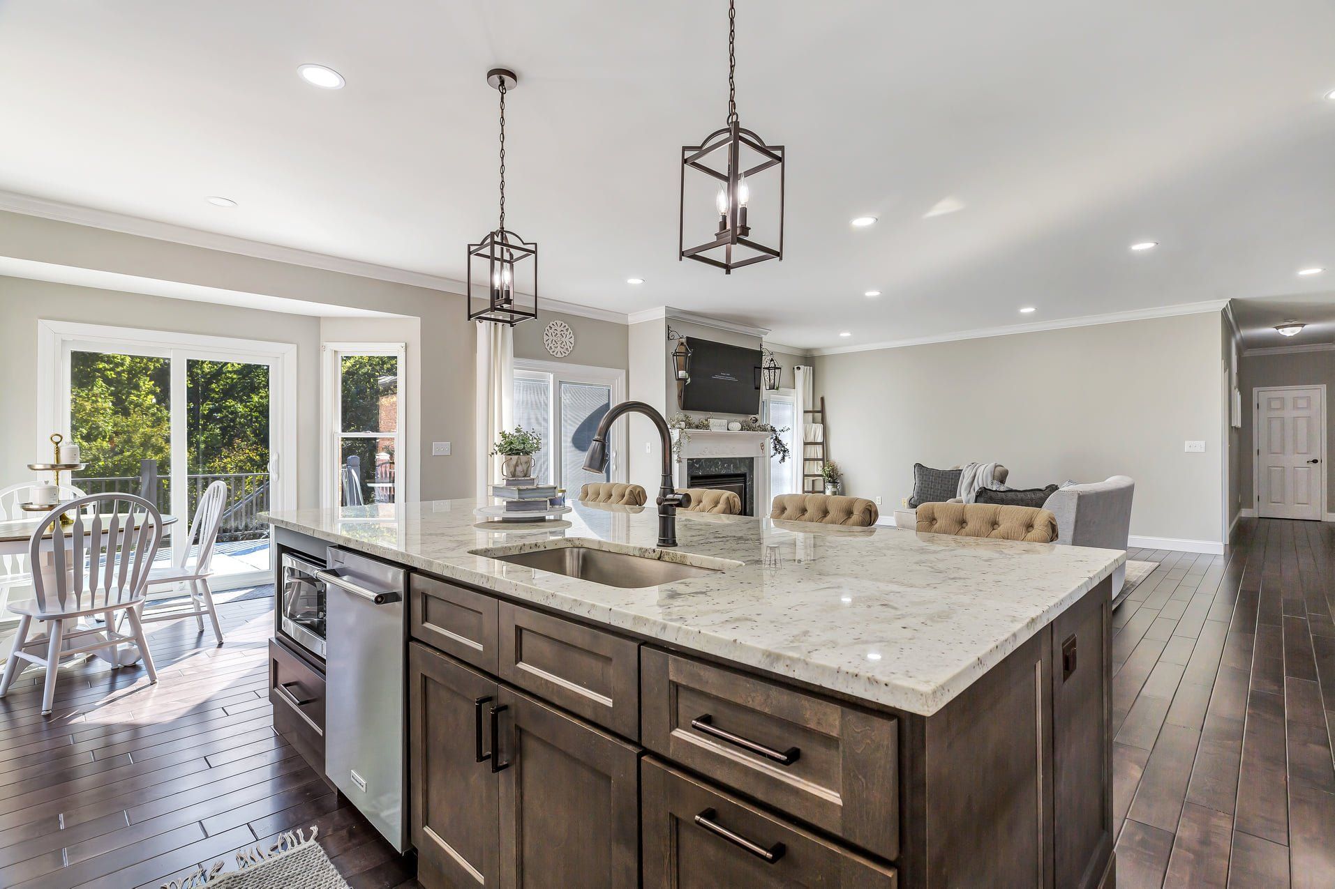 Bright modern kitchen with large island, pendant lights, dark wood floors, and adjacent dining area
