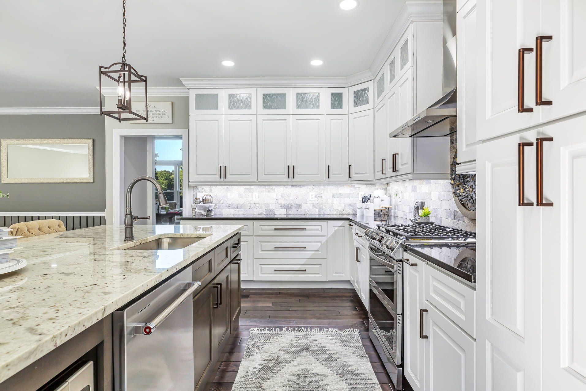 Bright white kitchen with marble island, stainless appliances, and pendant lighting