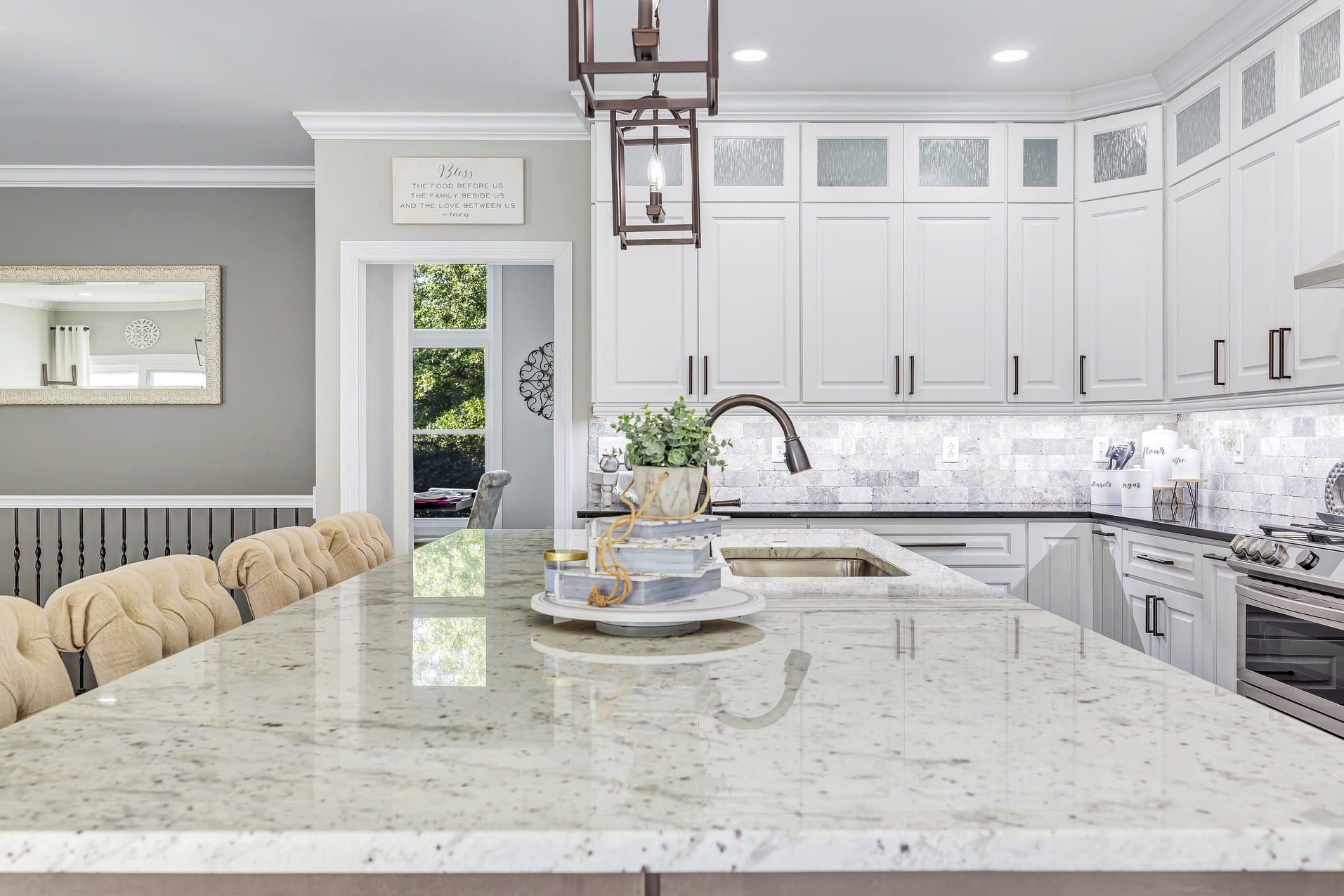 Bright modern kitchen with white cabinets, marble island, and pendant lights