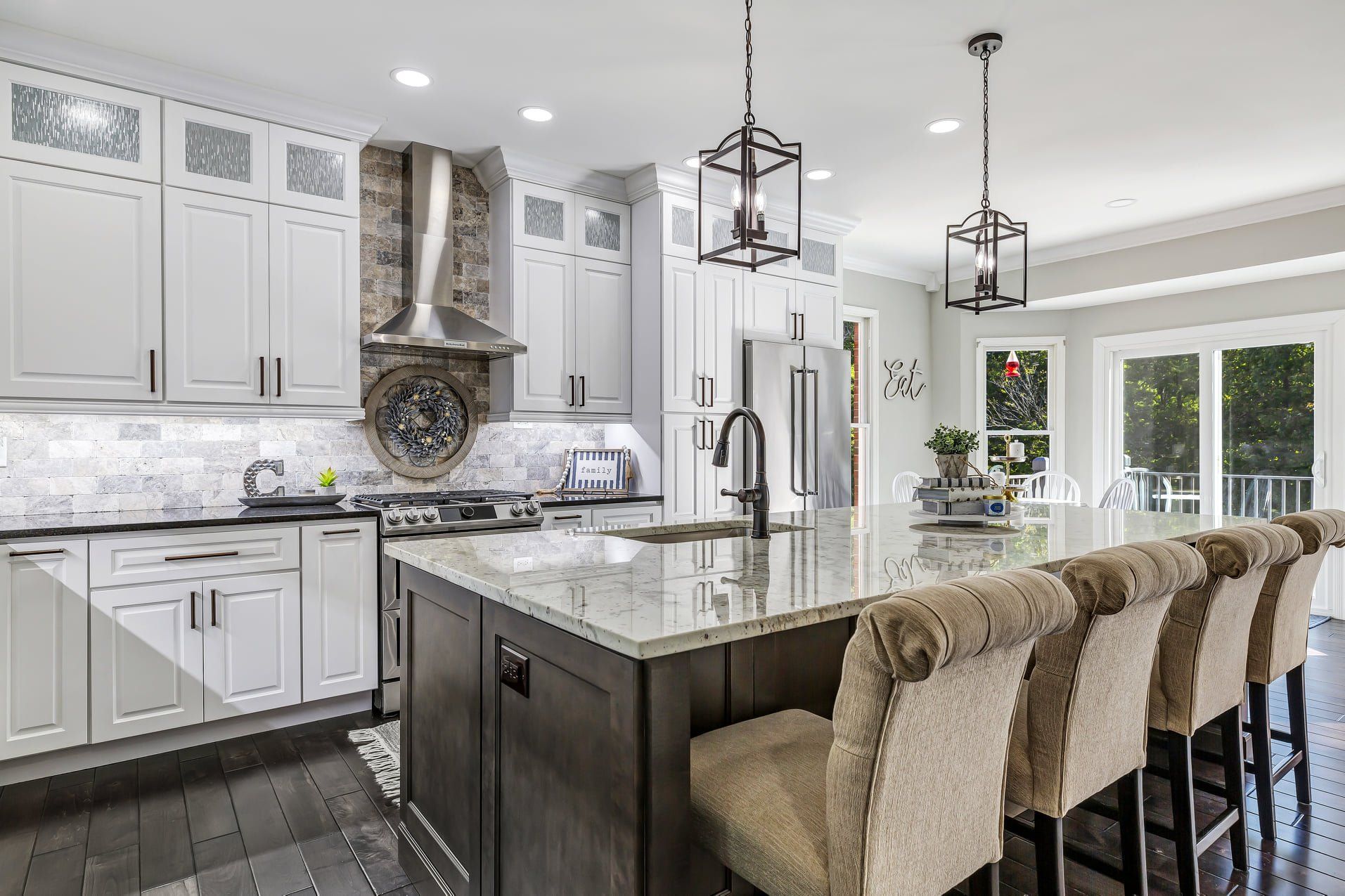 Bright modern kitchen with white cabinets, marble island, pendant lights, and fur-covered bar stools.