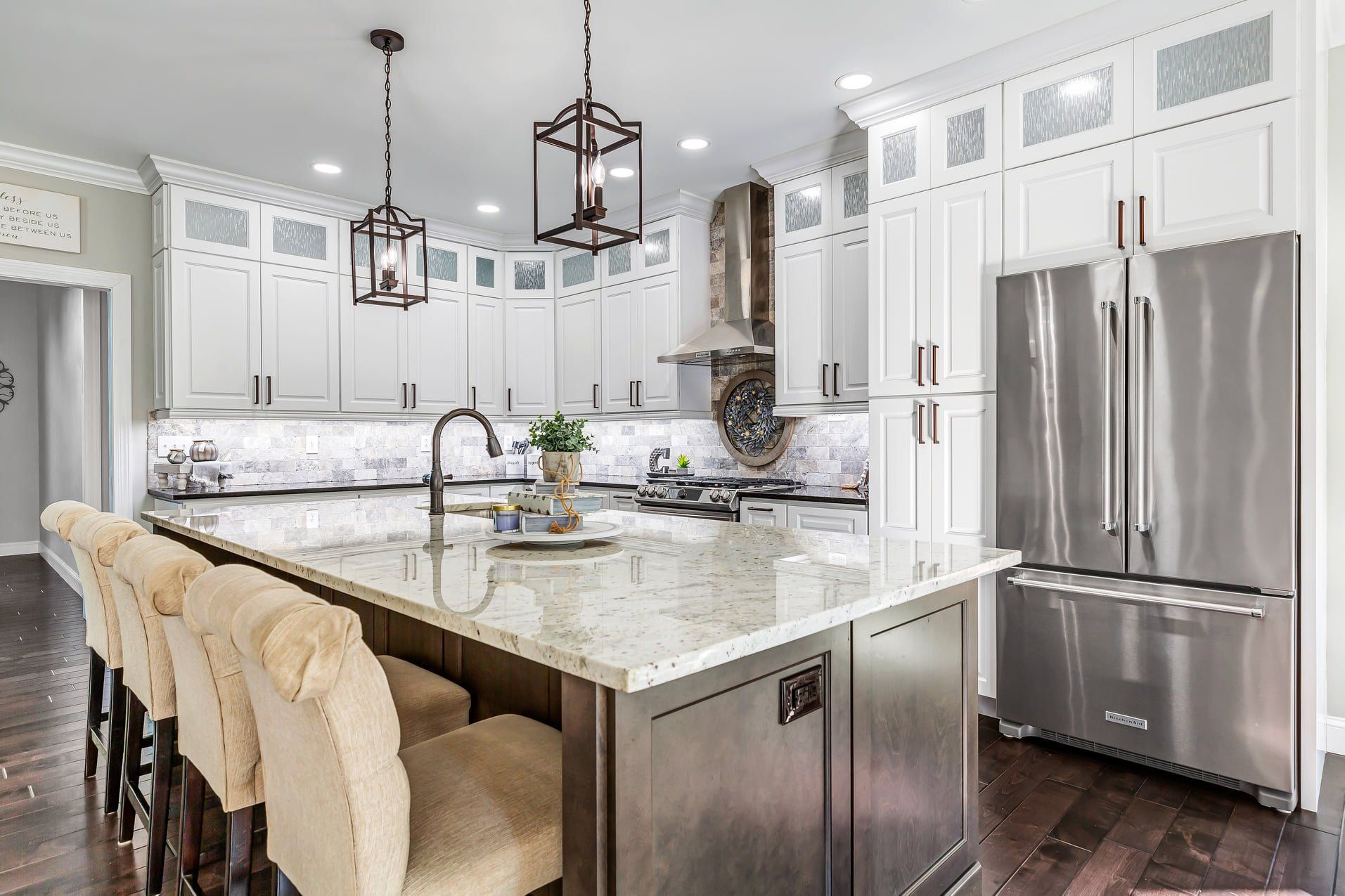 Bright modern kitchen with white cabinets, marble island, and stainless steel refrigerator