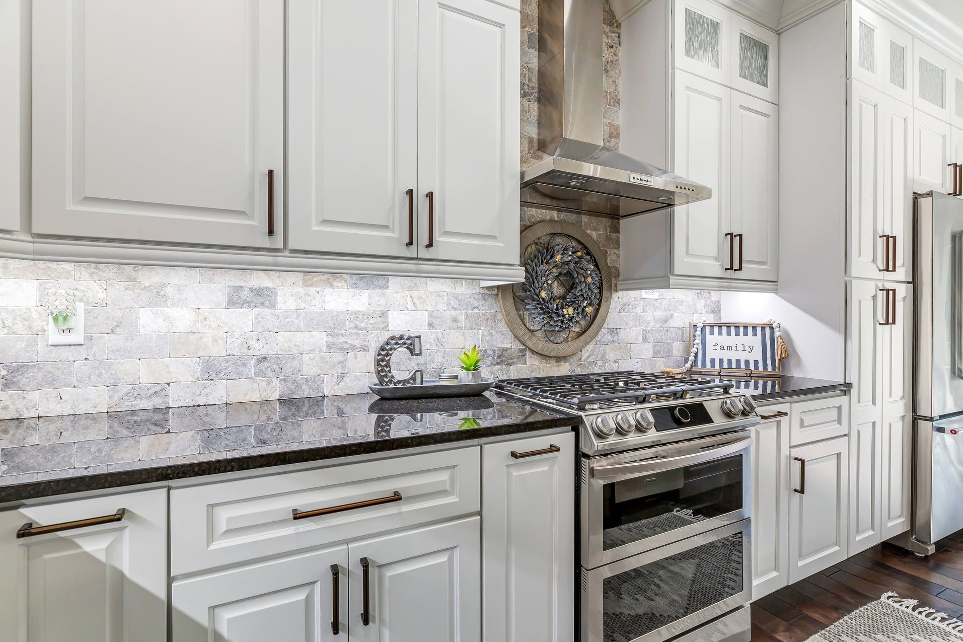 Bright white kitchen with marble backsplash, stainless steel range, and light gray cabinetry