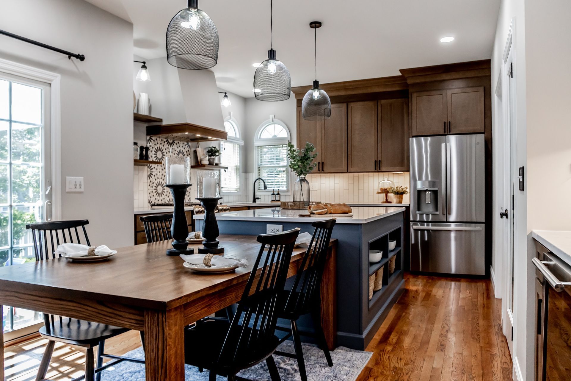 Modern kitchen and dining area with wood cabinets, stainless fridge, island, and pendant lights