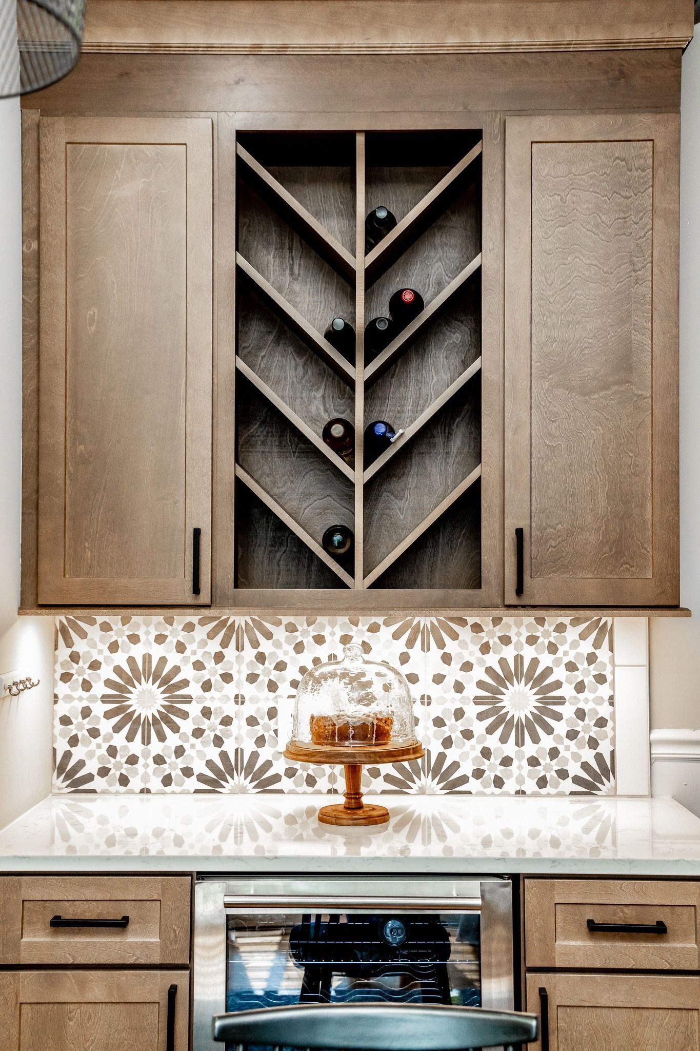 Built-in kitchen cabinets with a wine rack, marble backsplash, and espresso machine below