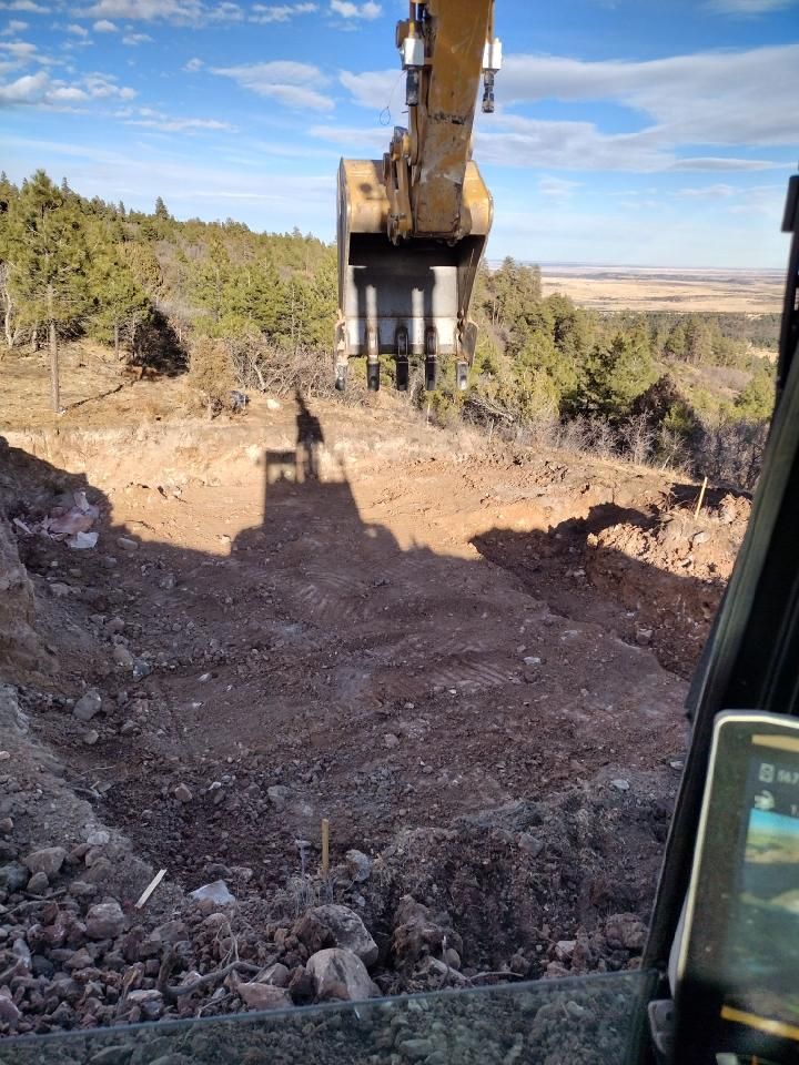 A bulldozer is digging a hole in the ground on a hill.