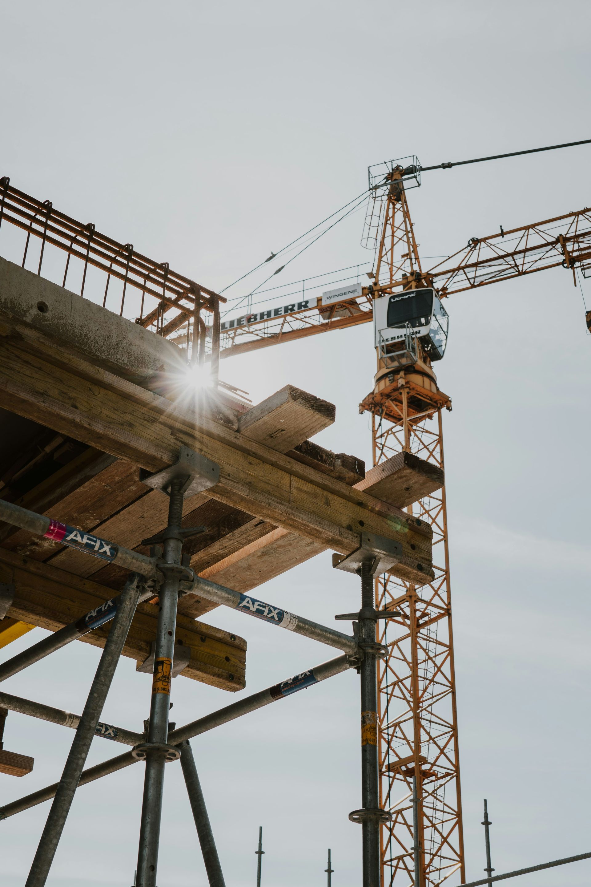 Drone Construction site with a crane beside a concrete building frame against a bright sky