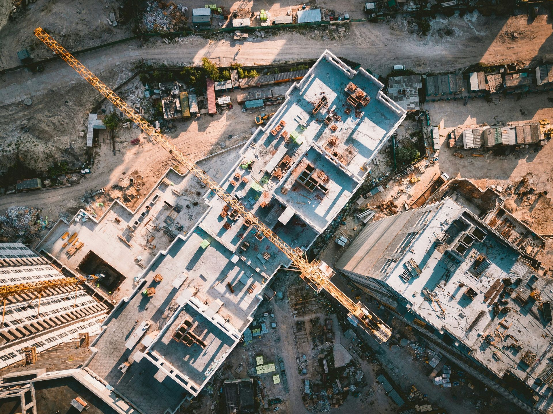 Drone Aerial view of a construction site with several partially built concrete buildings and cranes.