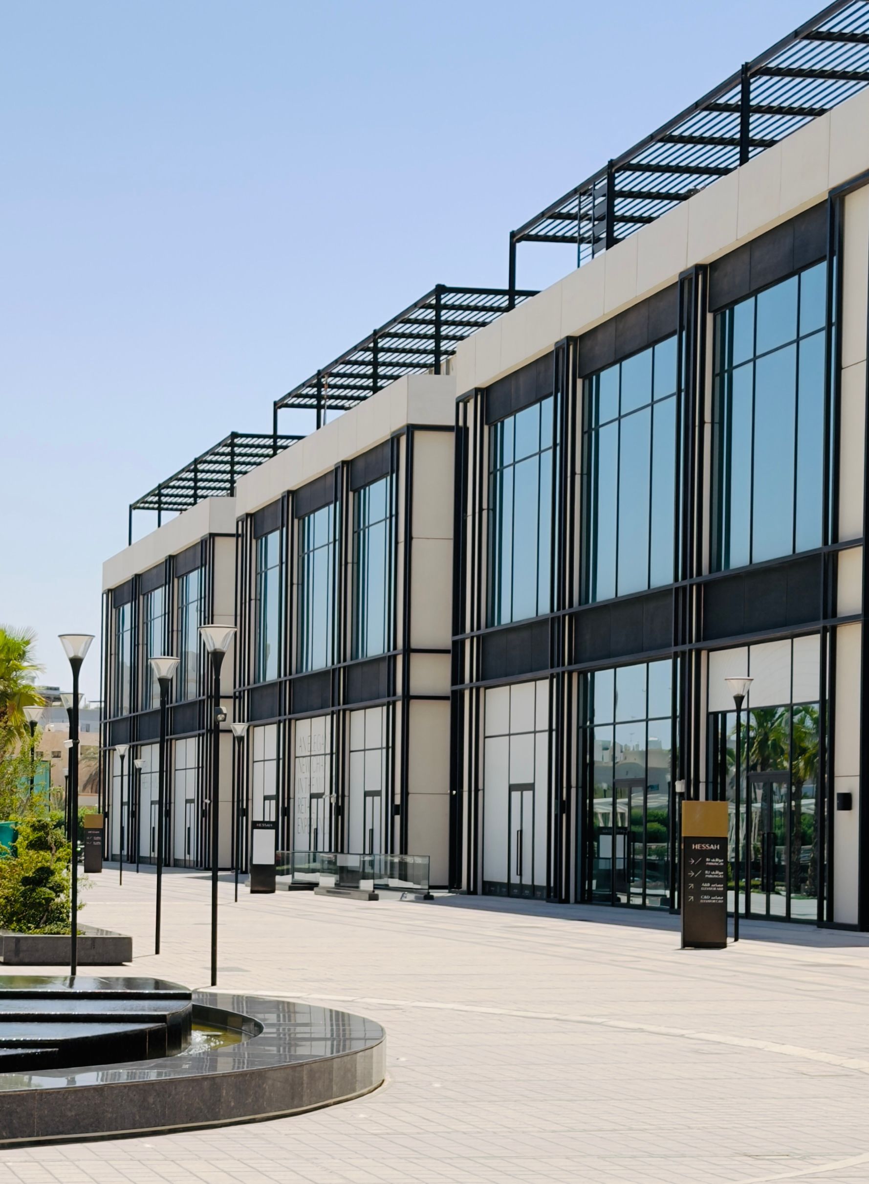 Drone Modern glass-fronted building with a paved courtyard and planter in front