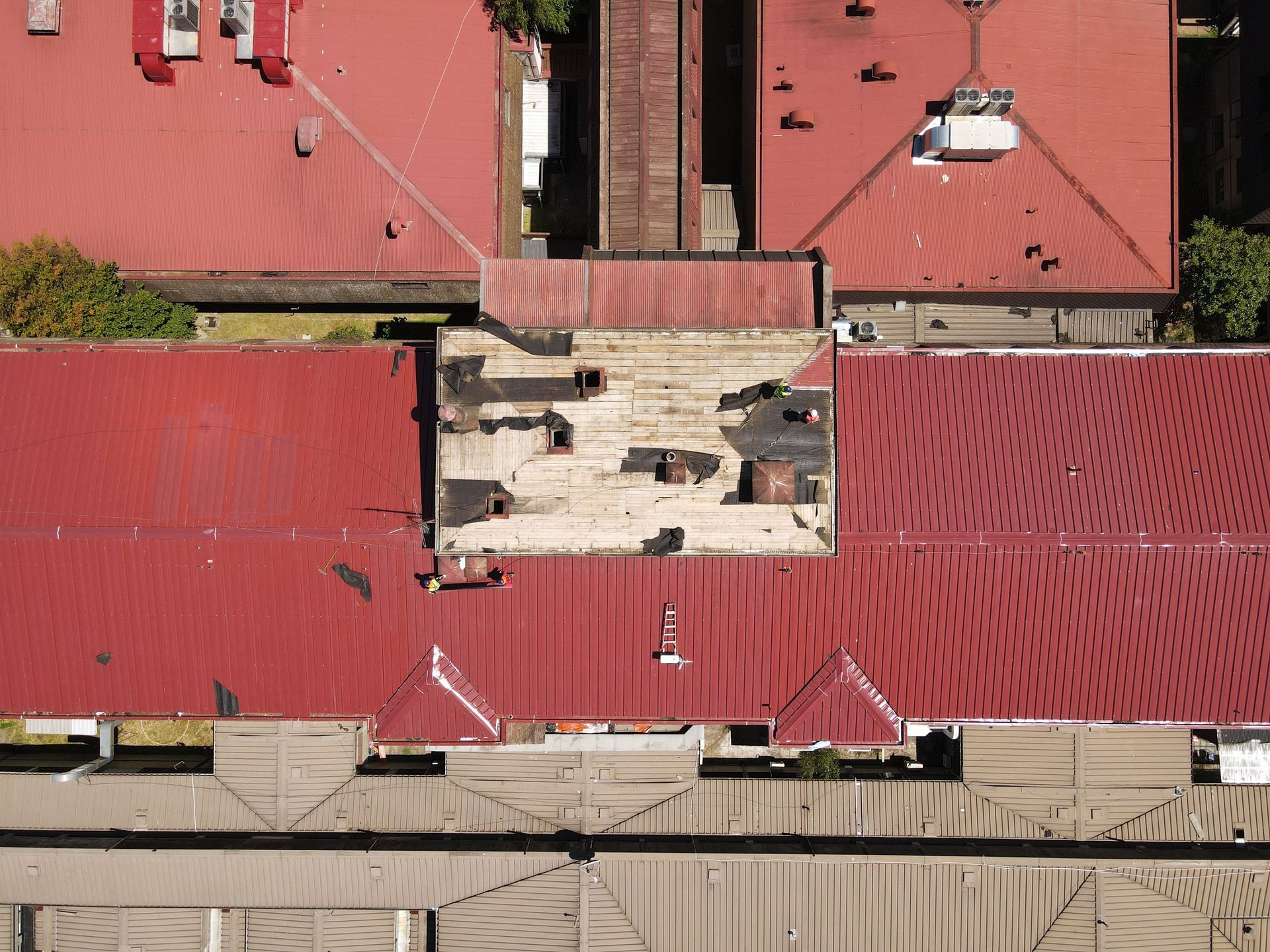 Drone Aerial view of red-roofed buildings with a central white rooftop section and rooftop equipment.