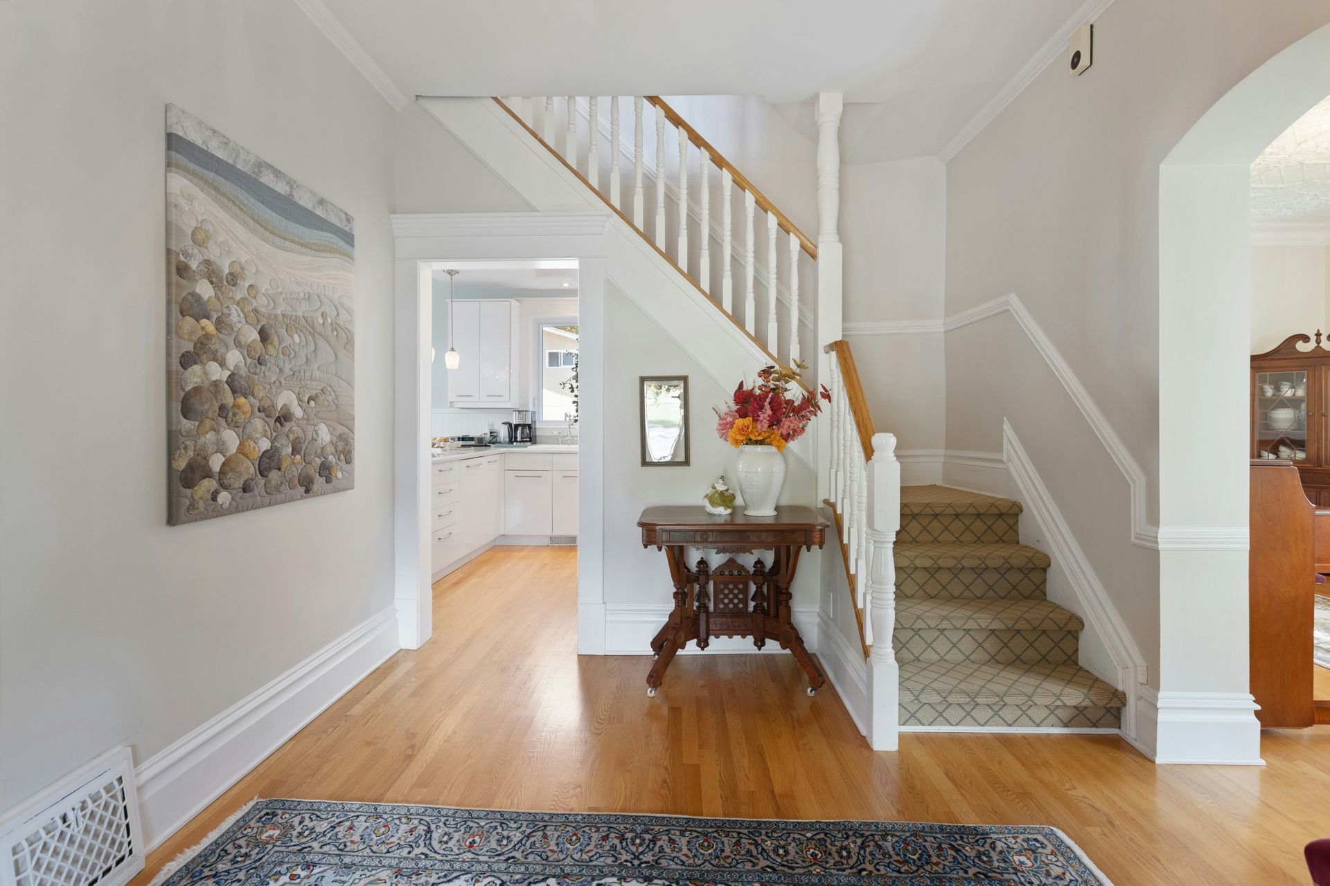 Drone Bright foyer with staircase, hardwood floors, console table, and floral arrangement
