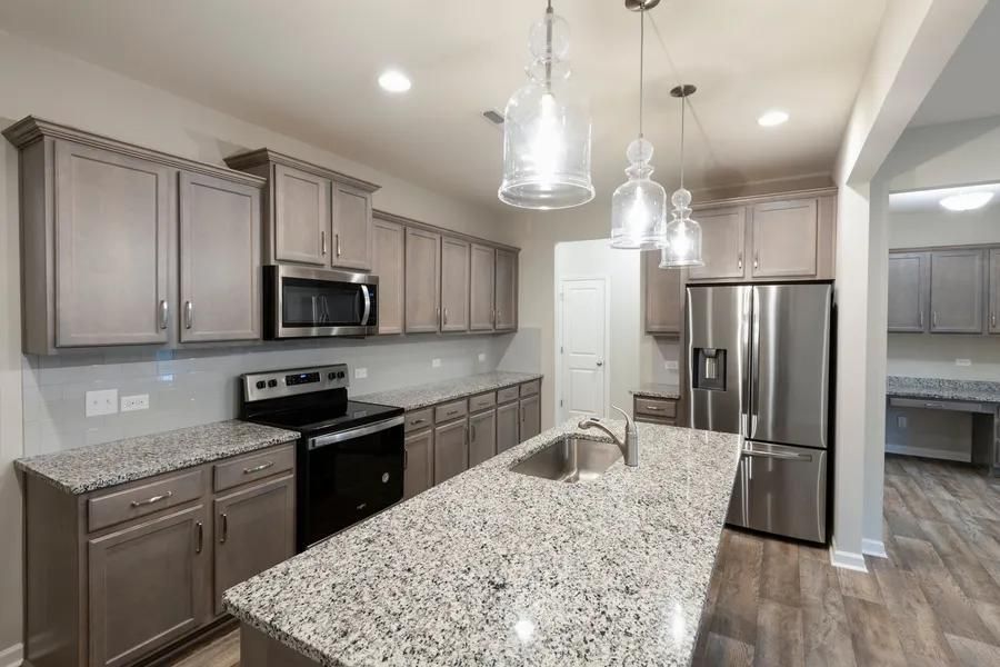 Kitchen with gray cabinets, granite countertops, stainless steel appliances, and pendant lights.