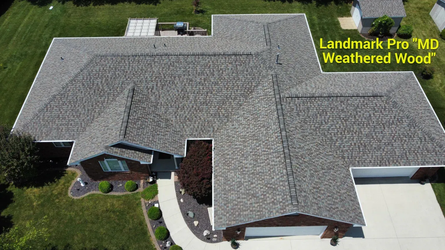An aerial view of a residential house roof with Landmark Pro Weathered Wood asphalt shingles.