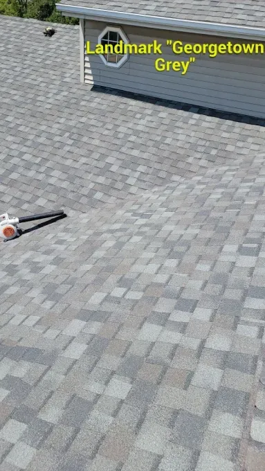 A view of a roof with Landmark Georgetown Grey asphalt shingles, featuring an octagonal window on the dormer above.