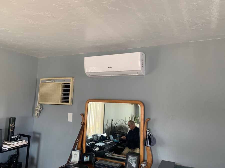 Gray room with wall AC units, mirror, and a desk reflected in the mirror