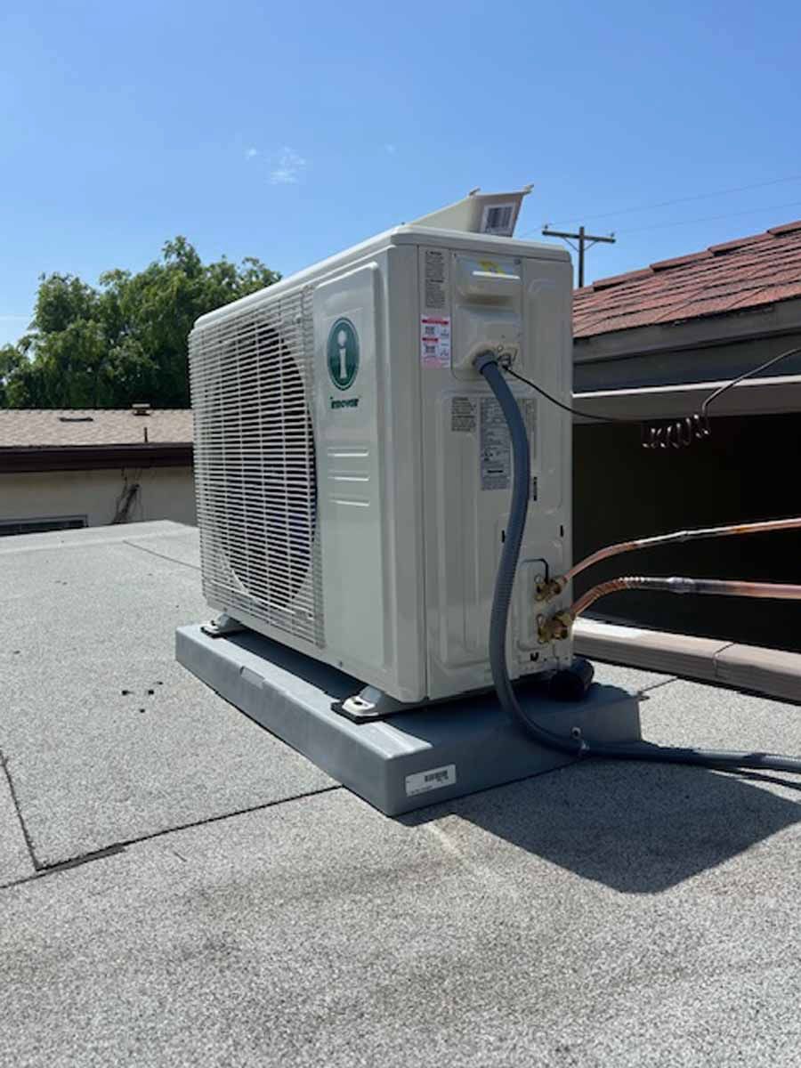 Outdoor HVAC unit on a rooftop platform beside a building under a clear blue sky