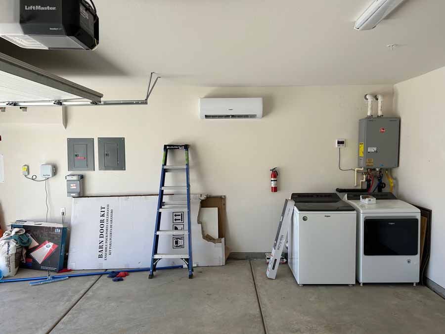 Garage interior with ladder, washer, utility sink, water heater, and storage items against the walls