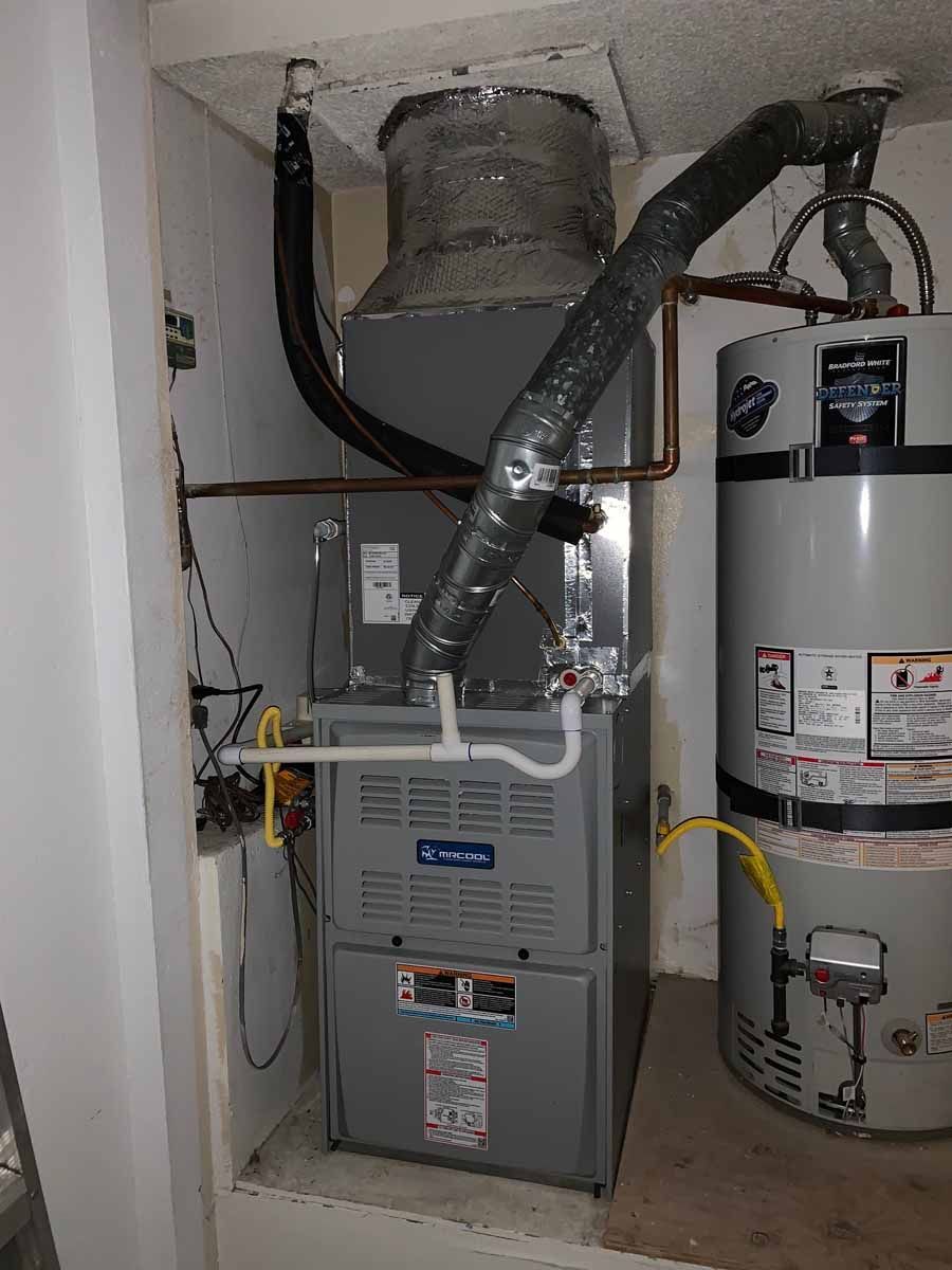 Utility closet with a furnace and water heater, connected by ductwork and pipes.