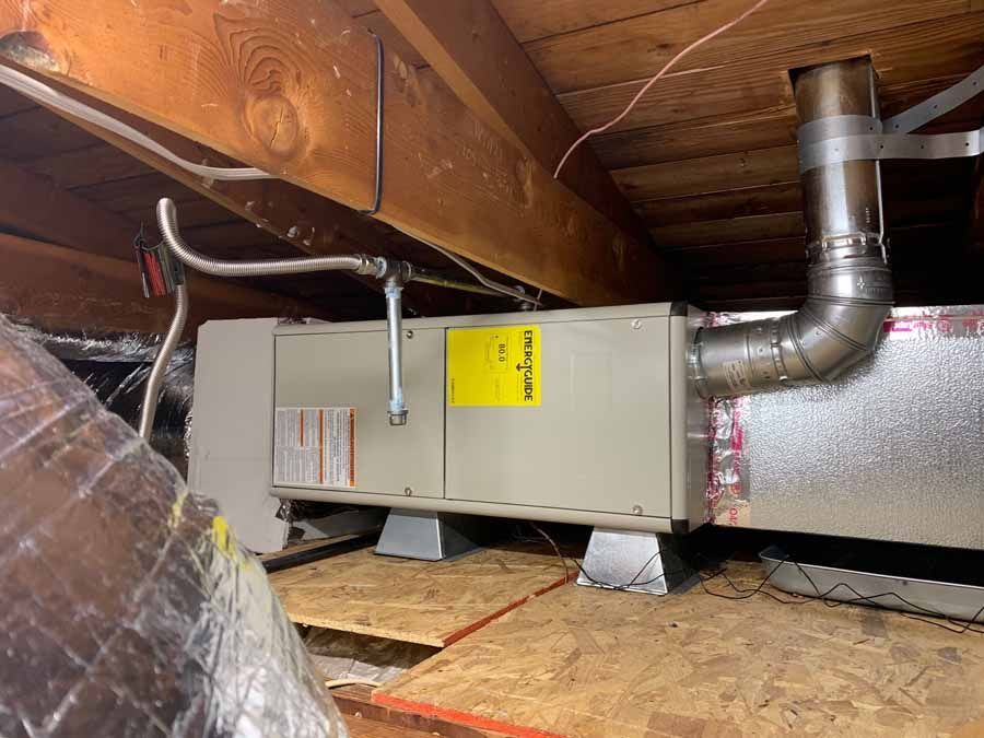 HVAC furnace and ductwork in a cramped attic crawlspace