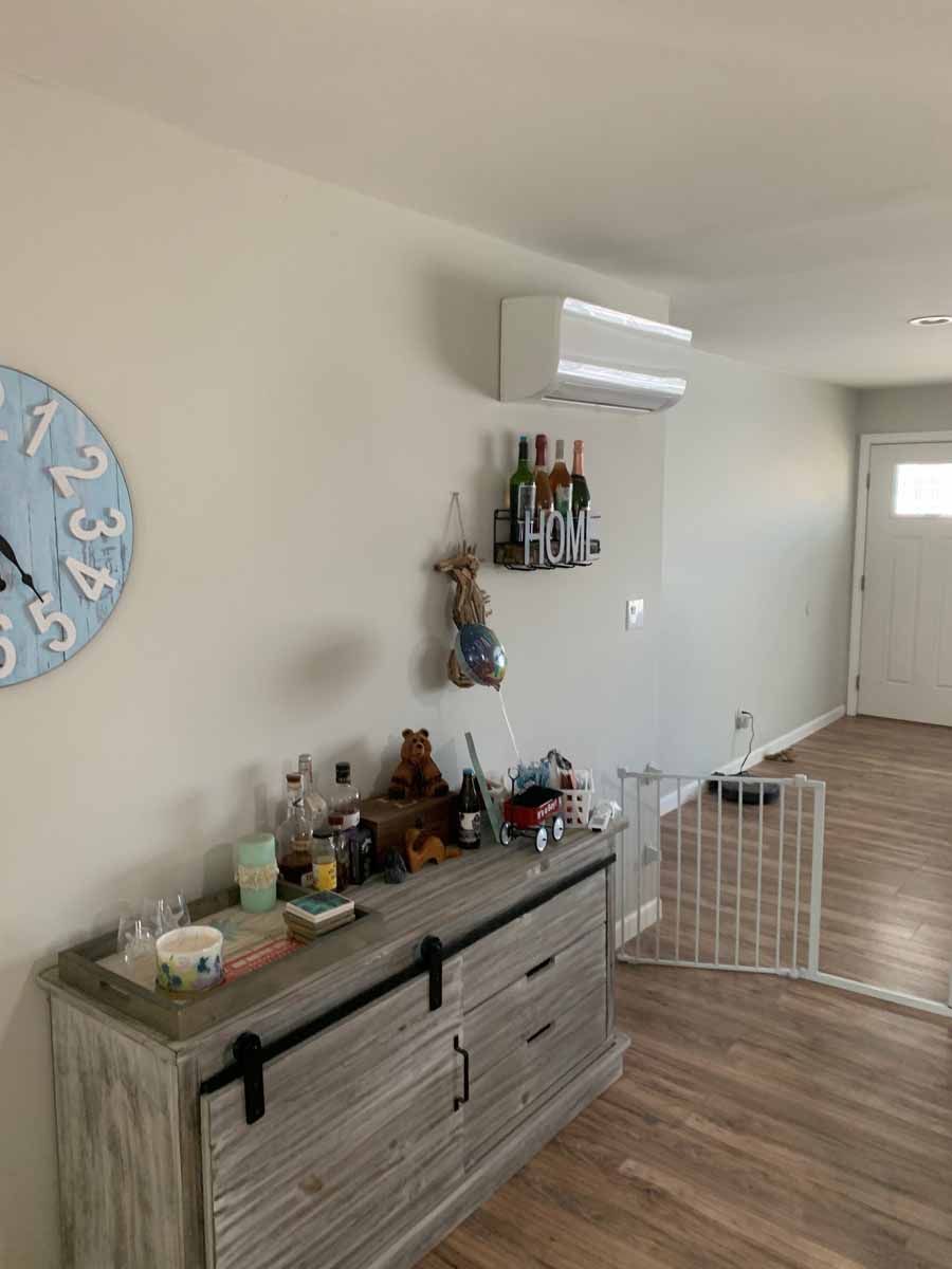 Living room sideboard with decor, wall clock, and wall-mounted shelf under an air conditioner.