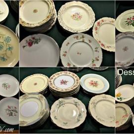Assorted vintage floral china plates and saucers stacked and spread on a dark table.